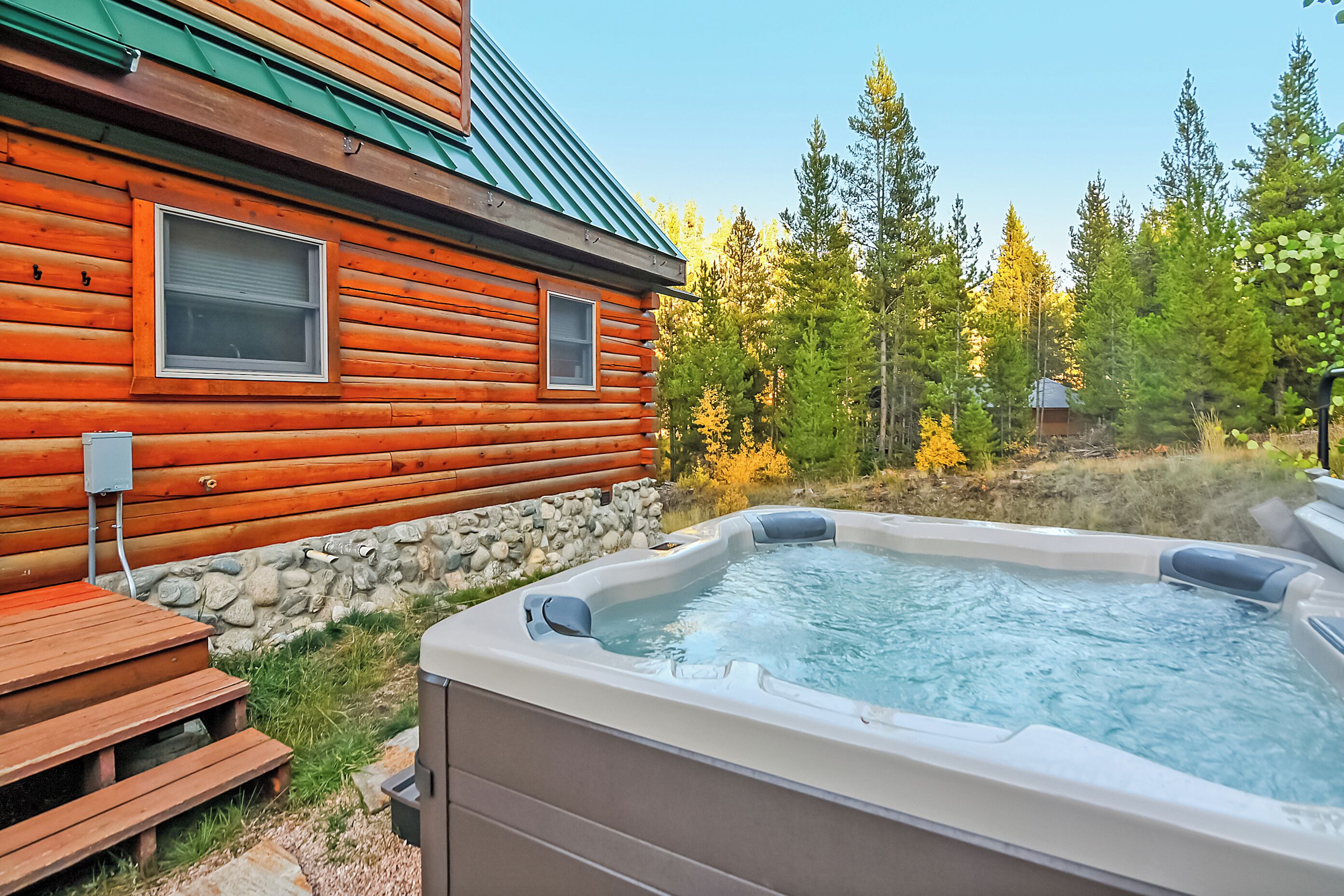 A log cabin with a hot tub and wooden deck.