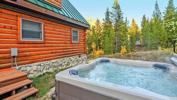A log cabin with a hot tub and wooden deck.