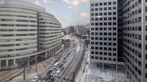 A multi-story building with a curved facade and a flat roof, adjacent to a straight building with a grid of windows. - Modern Apt Downtown (Stamford, CT)