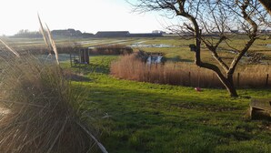 A rural landscape with fields, a tree, and a wooden structure. - Opas Hus auf Pellworm (Pellworm)