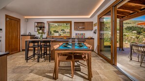 A modern kitchen with a dining area, large windows, and a view of the countryside. - Villa sulla Roccia, privacy e relax. (Sicilia)