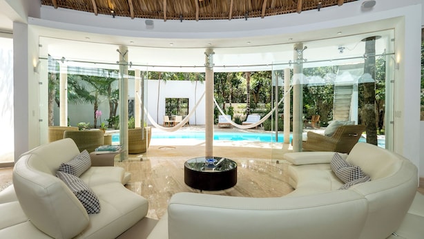A modern living room with a glass wall overlooking a pool and garden.