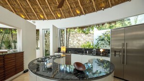 A modern kitchen with a curved island, stainless steel appliances, and a stone accent wall.