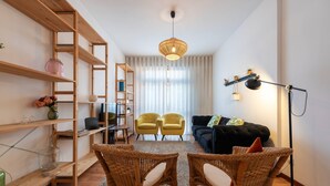 Ein modernes Wohnzimmer mit Holzbögen, Korbstühlen, einem schwarzen Sofa und einer Stehlampe.