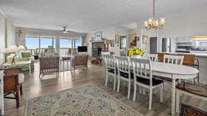 A spacious living room with a dining area, a kitchen, and a view of the ocean.