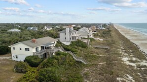 A coastal residential area with houses, a beach, and a clear sky.