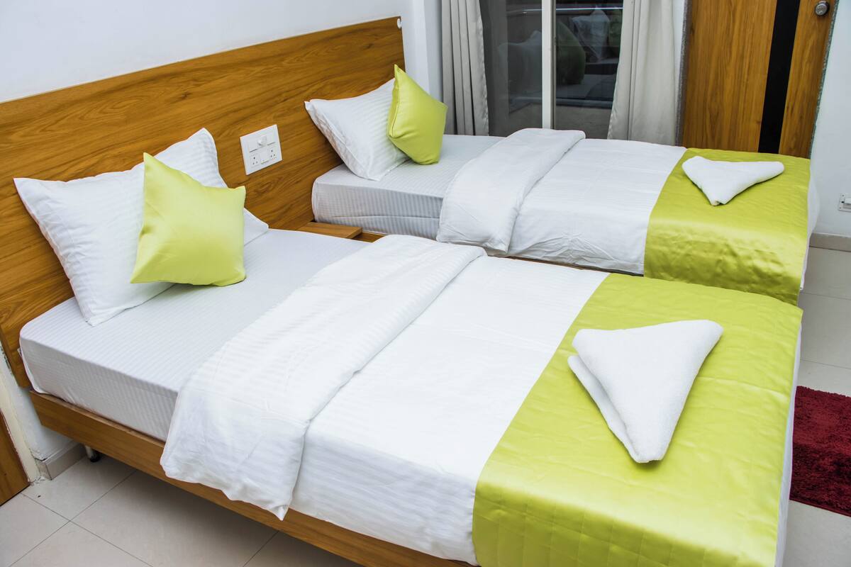 Un lit double avec une tête de lit en bois, deux oreillers et une couvre-lit verte.