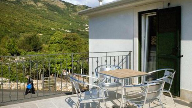 A balcony with a table and chairs, a door, and a view of a mountainous landscape. - Charming studio with balcony, WiFifree parking and AC in adorable old town Brseč (Brsec)