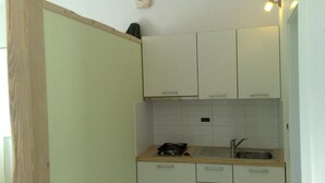 A compact kitchen with white cabinets, a wooden countertop, a gas stove, and a sink. - Charming studio with balcony, WiFifree parking and AC in adorable old town Brseč (Brsec)