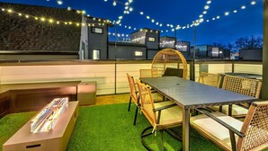 Un patio al aire libre con una mesa, sillas, luces colgantes y una jaula decorativa.