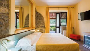 A bedroom with a bed, a bedside lamp, a TV, and a stone wall. - Country House Abate Pool Ac Wifi Potenza (Trivigno)