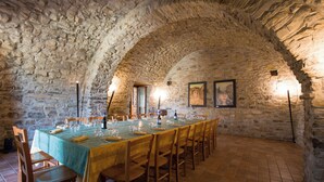 A stone-walled dining room with a long table set for a meal, wooden chairs, and a tiled floor. - Country House Abate Pool Ac Wifi Potenza (Trivigno)
