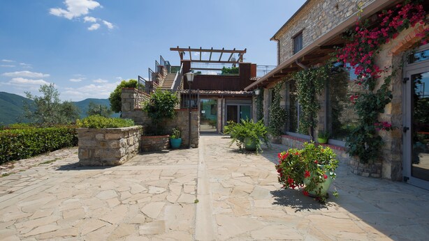 A stone courtyard with a pergola, potted plants, and a view of the mountains. - Country House Abate Pool Ac Wifi Potenza (Trivigno)