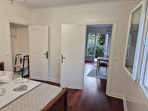A bedroom with a bed, a chair, a wardrobe, and a door leading to a balcony.