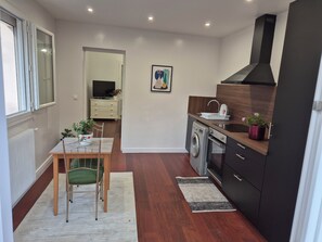 A compact kitchen with a washing machine, a sink, and a dining area with a table and chairs. - Renovated one-bedroom apartment in a quiet neighborhood with a flower-filled terrace (Le Raincy)
