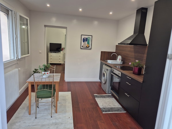 A compact kitchen with a washing machine, a sink, and a dining area with a table and chairs.