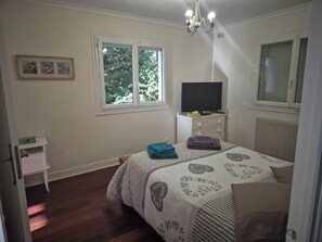 A bedroom with a bed, a dresser, a television, and a window.