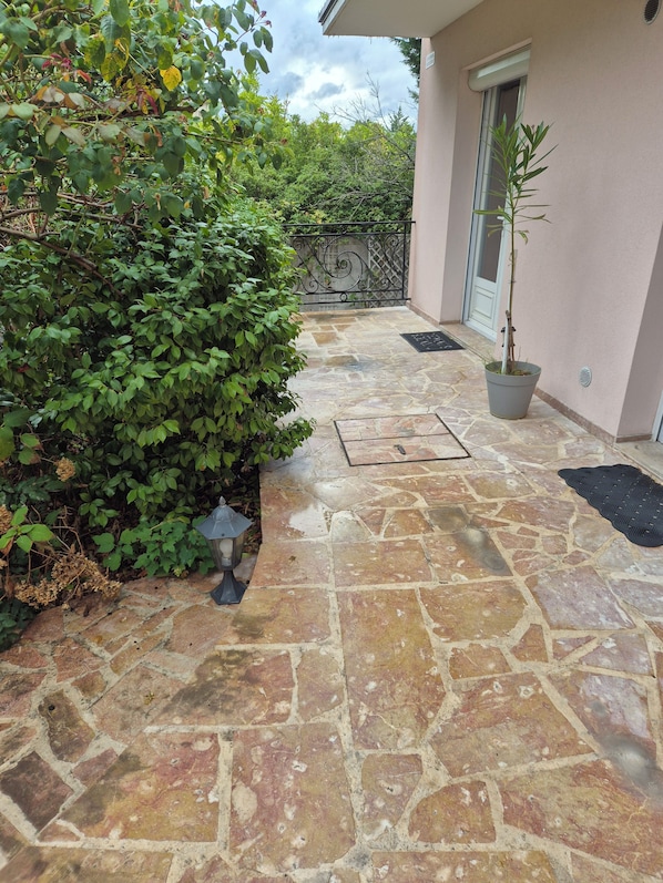 A stone-tiled patio with a potted plant and a metal lantern.