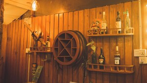 A wooden interior with a large wooden wheel, shelves with bottles, and a light fixture. - Gypsy hostel & Backpackers (Pokhara)