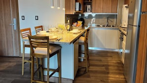 Une cuisine moderne dotée d’un îlot central, de chaises en bois, d’un four encastré et d’un réfrigérateur.
