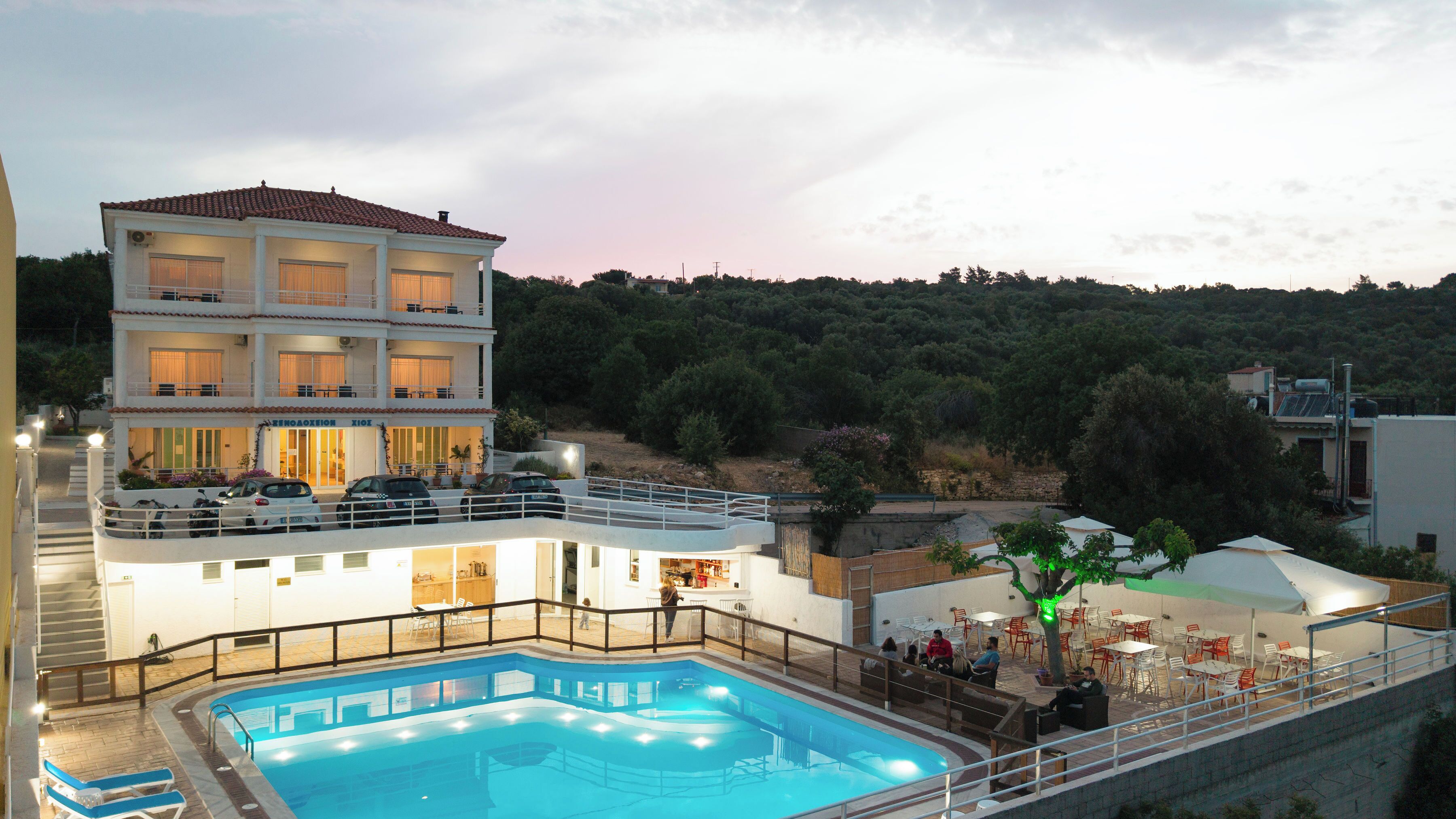 A hotel with a swimming pool, outdoor seating, and a view of the surrounding hills.