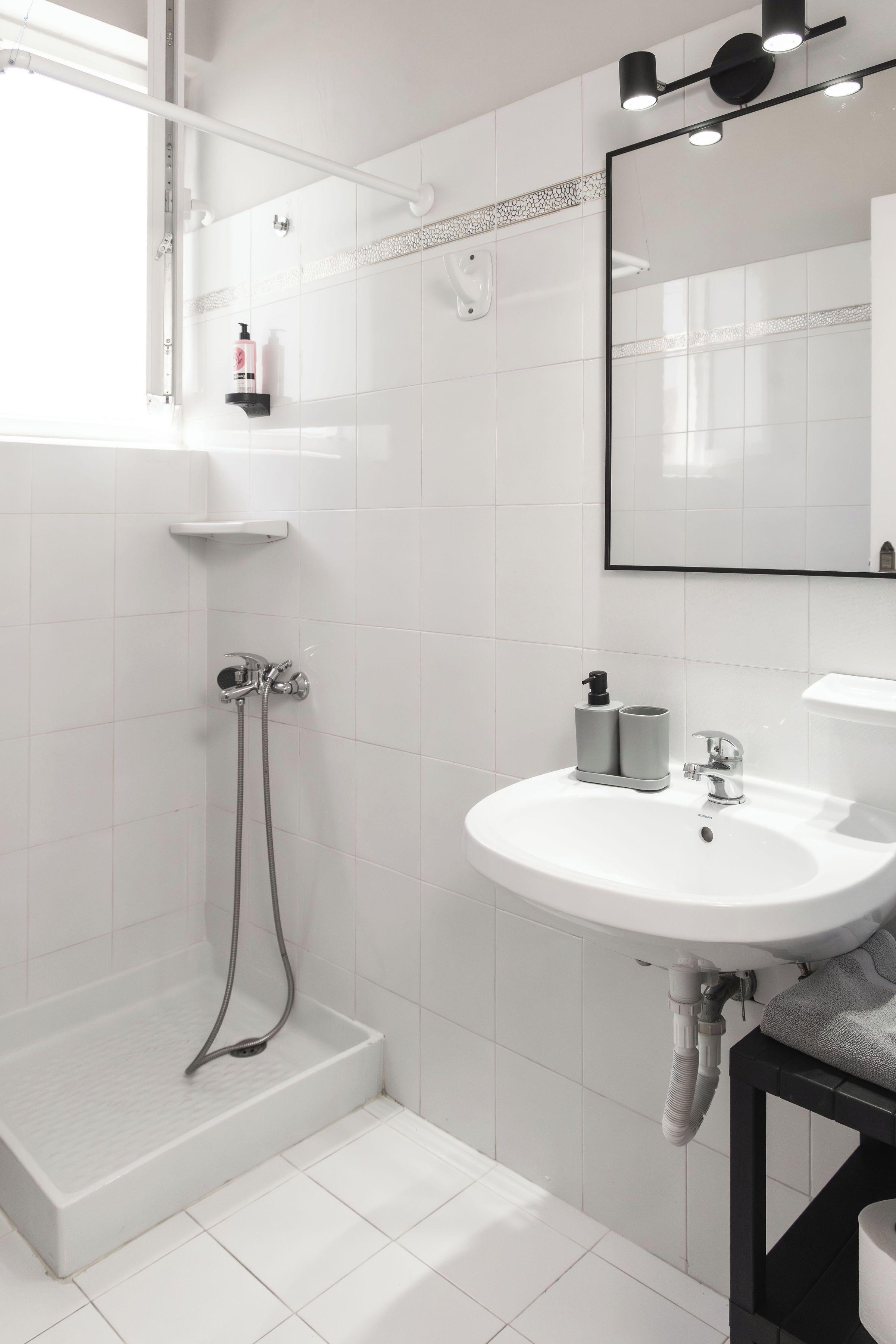 A modern bathroom with a white sink, a shower, and a mirror.