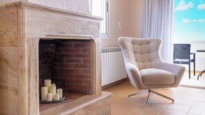 A fireplace with candles, a modern armchair, and a view of the outdoors.