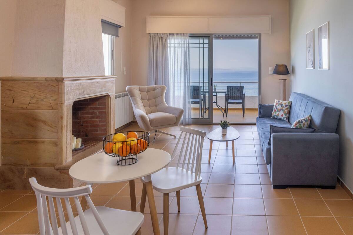 Una sala de estar con chimenea, un sofá, una mesa de comedor con sillas y un balcón con vistas.