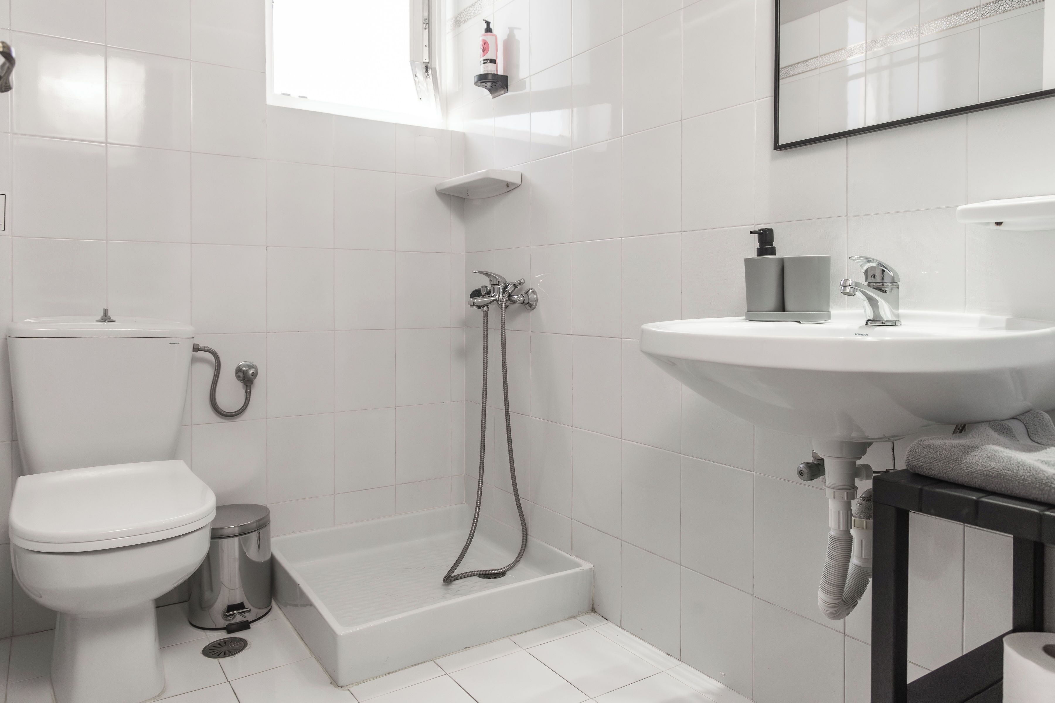 Un baño con inodoro, ducha, lavamanos y un perchero para toallas.