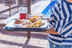 A tray with croissants, a croissant sandwich, a croissant with chocolate, a croissant with jam, and a glass of red drink.