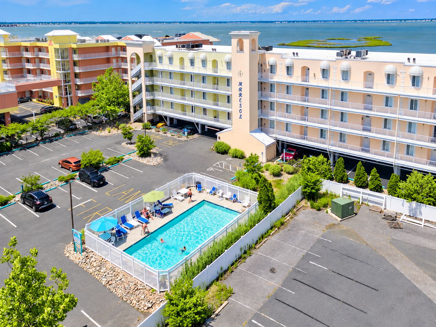 A hotel with a swimming pool, multiple balconies, and a view of the sea.