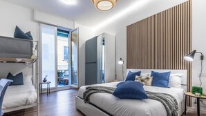 A modern bedroom with a large bed, a built-in wardrobe, a small bedside table, and a view through a glass door to an outdoor area. - Elegant & Spacious 3-Bedroom Apartment in Milan’s Historic Center (Milano)