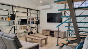 Un soggiorno moderno con un divano grigio, un tavolino in legno ed una libreria piena di libri e oggetti decorativi.