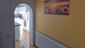A hallway with a yellow wall, a radiator, and a painting of sunflowers. - Cosy 1BR Hideaway - Hot Tub, Wifi & Private Pond (Newark)