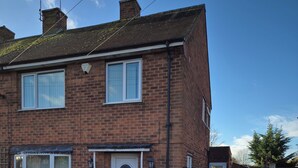 A residential building with a brick facade, a garage, and a parked car. - Cosy 1BR Hideaway - Hot Tub, Wifi & Private Pond (Newark)