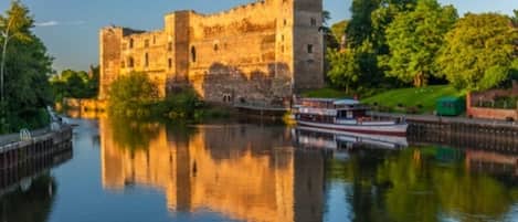 Eine historische Burg an einem ruhigen Fluss, mit einem vertäuten Boot in der Nähe.