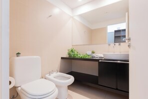 A modern bathroom with a toilet, bidet, and a sink with a mirror above. - MOT LIVE HOTEL (Buenos Aires)