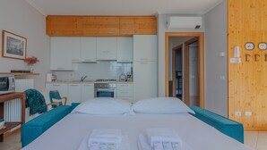 Une chambre d’hôtel avec un lit, une petite kitchenette, un plafond en bois et une porte en bois.