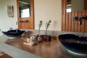 Un baño con dos recipientes grandes azules, paneles de madera, un espejo y un perchero para toallas.