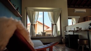 A cozy room with a sofa, a small table, and a window with curtains. - Lavandas de Cunha Pousada Boutique (Cunha)