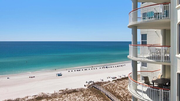 A beachfront hotel with a balcony overlooking the ocean, a sandy beach, and a clear sky. - 🏝️Huge Balcony w/Gulf Views ☀️ Beach Colony Resort East 11A (Navarre Beach)