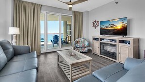 A modern living room with a sofa, a coffee table, a television, and a view of the outdoors. - 🏝️Huge Balcony w/Gulf Views ☀️ Beach Colony Resort East 11A (Navarre Beach)