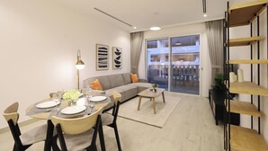 A modern living room with a dining area, a sofa, a coffee table, and a bookshelf.
