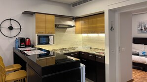 A compact kitchen with a microwave, toaster, and coffee maker on the counter, wooden cabinets, and a small island with a sink.