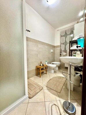 A modern bathroom with a toilet, bidet, and a small wooden side table. - Top Apartment (Castel D'Azzano)
