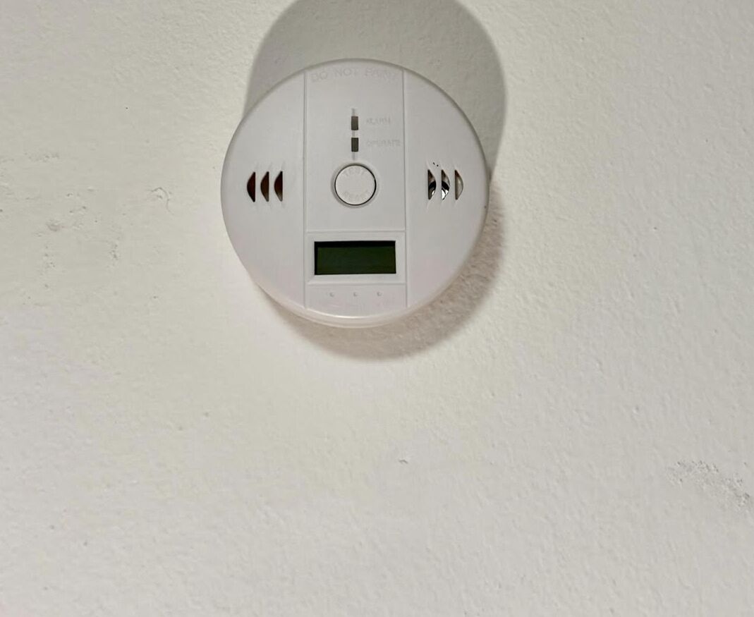 Detector de humo instalado en una pared blanca.