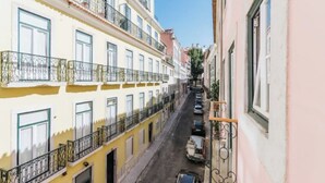 A narrow street with yellow buildings, balconies, and parked cars. - Quiet Prince - City Center Apartment (2D) (Lisboa)