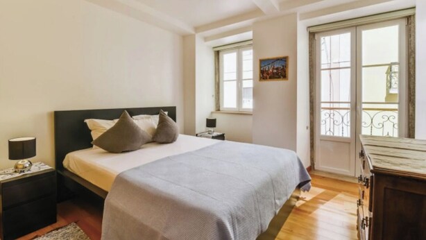 A bedroom with a bed, bedside tables, a nightstand, a dresser, and a window with a balcony view. - Quiet Prince - City Center Apartment (2D) (Lisboa)