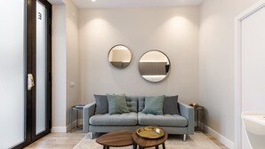 A modern living room with a grey sofa, two round mirrors, a small round table, and a wooden coffee table.