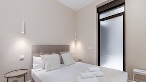 A modern bedroom with a large bed, a round side table, and a sliding door.